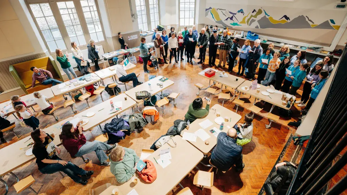 Attendees of singing workshop performing in hall. 