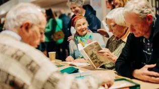 Woman looks in Gaelic dictionary while playing Scrabble. 