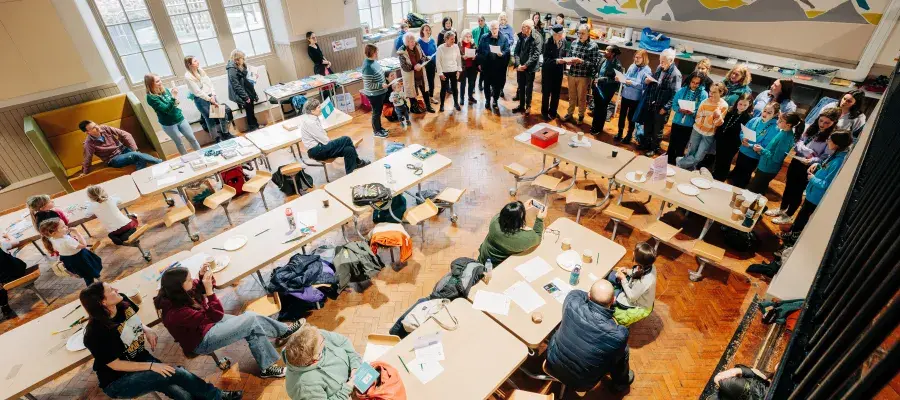 Group of people singing in community hall. 