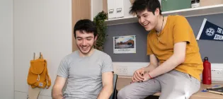 Two students looking at a laptop in University accommodation.