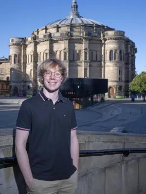 Graduate stands in front of McEwan Hall.